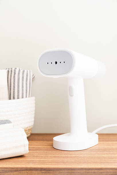 istock White handheld portable steamer next to laundry basket on table 2214434875