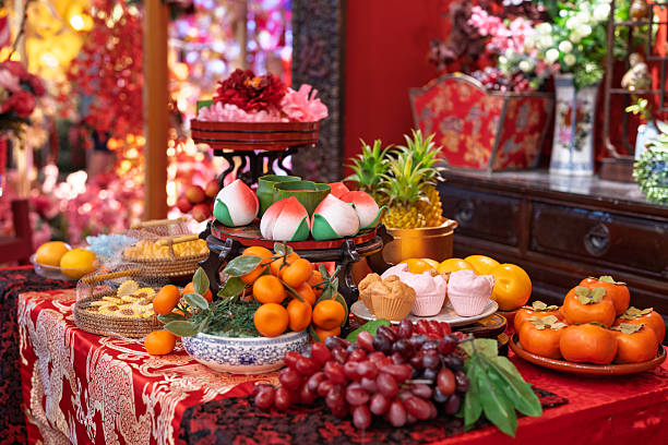 A beautifully decorated Chinese New Year offering table displaying traditional fruits, pastries, and longevity peach buns, symbolizing prosperity, health, and good fortune for the new year.