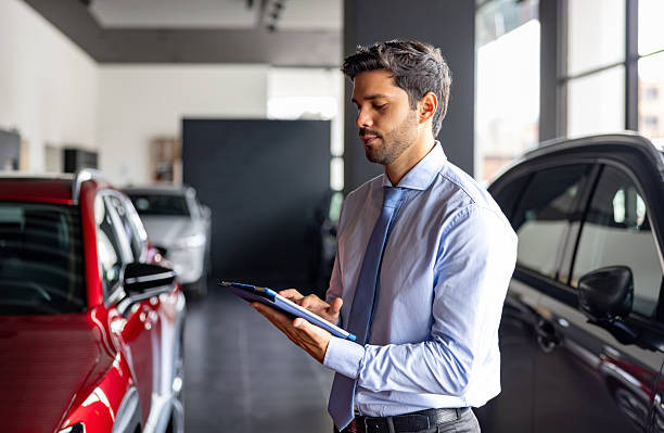 istock Car salesperson using a digital tablet while working at the dealership 2214444138