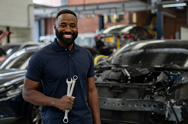 istock Mechanic working at a car garage and smiling while holding tools 2214445668
