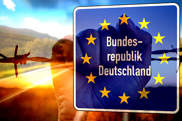 German border and a migrant holding the barbed wire in his hand