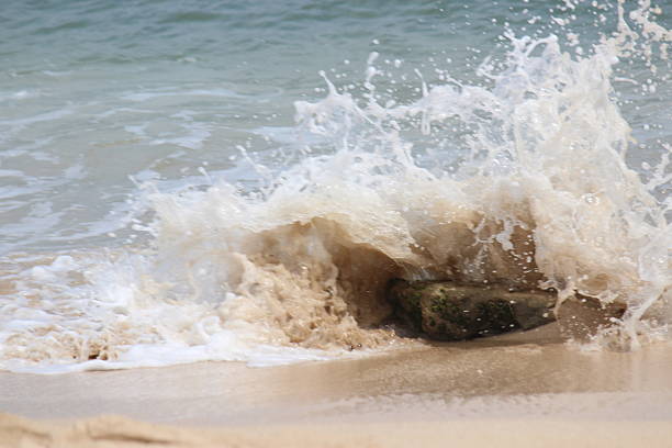 A DSLR Canon photo of a 12-year-old Brazilian girl jumping some waves on crystal clear turquoise water in Fernando de Noronha on a bright sunshine day. Praia do Boldró, Fernando de Noronha, Pernambuco, Rio de Janeiro.