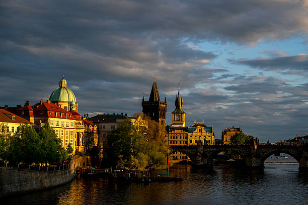 Prague, czech republic - september 5, 2025: scenic view of prague from vysehrad highlights the vltava river, historic buildings, lush greenery, and a dramatic sky