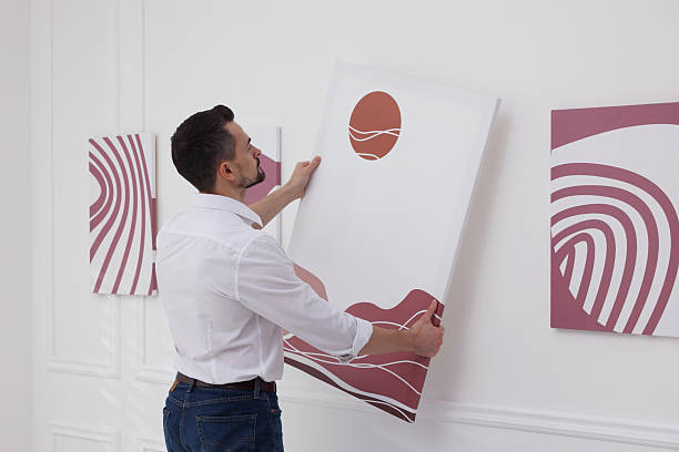 istock Man hanging painting on wall in art gallery 2214460649