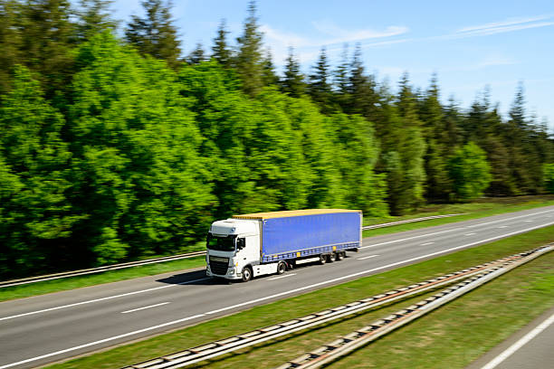 Traffic driving on a highway through a forest with spring colors during a springtime day seen from above. The highway A50 runs through the Veluwe nature reserve in Gelderland, Netherlands. Photo with panning motion blur.