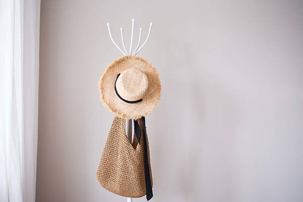 Beautifully stylish and trendy straw hat alongside a fashionable bag are displayed elegantly on a minimalist coat rack