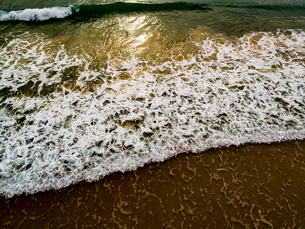 Aerial view Top down Waves crashing on sandy shore,Dark sea surface in summer day background,Seascape top view waves at Phuket Thailand