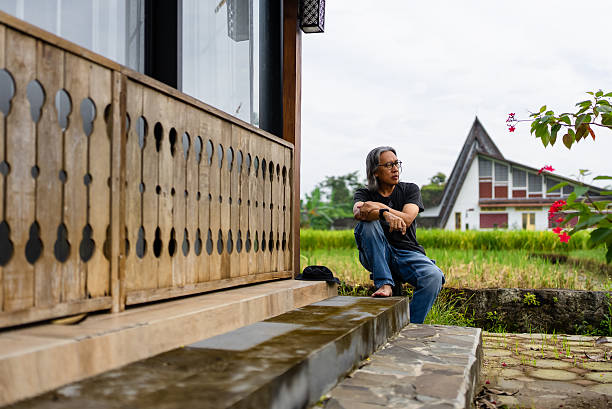 Tourist in outdoor clothing sitting on a porch of chalet and checking his phone.
