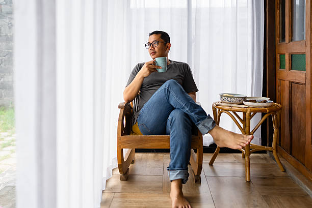 istock man picking up coffee cup sitting at table in home 2214466785