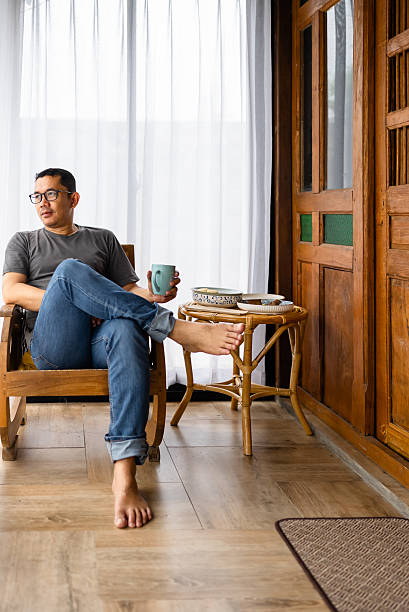 istock man picking up coffee cup sitting at table in home 2214466791