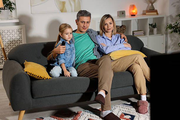 istock Family watching TV on sofa at home 2214467344