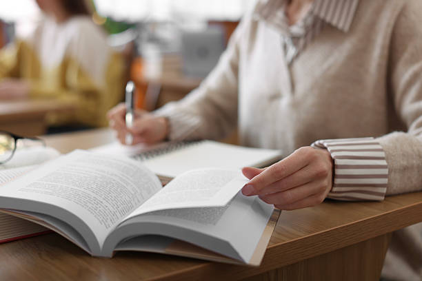 istock Woman reading book and taking notes at desk in library, closeup 2214468261