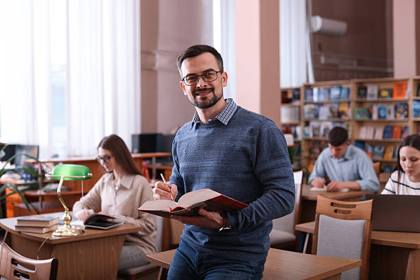 istock Portrait of smiling man with book in library 2214468286