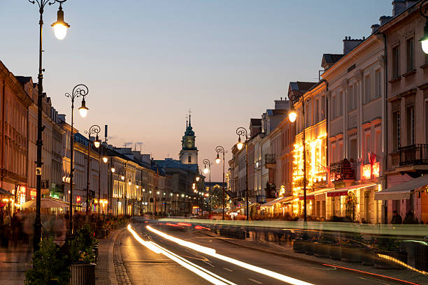Old town at dusk with motion blur traffic and Church of the Holy Cross in distance, Warsaw