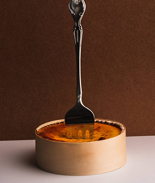 Gourmet Cheesecake with Fork on Wooden Base and Brown Backdrop