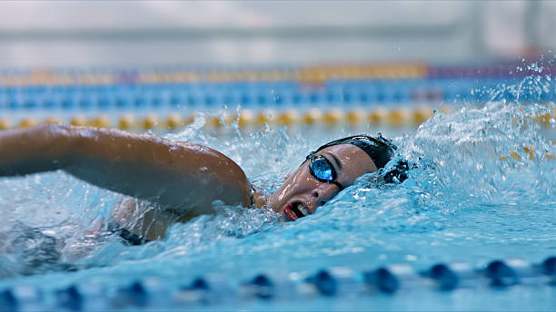 istock Swimmer in goggles races through indoor pool, training for water sport. 2214474954