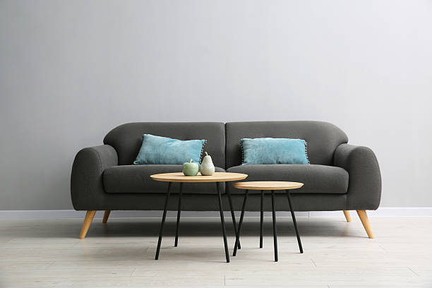 istock Comfortable sofa and tables near grey wall in room 2214477142