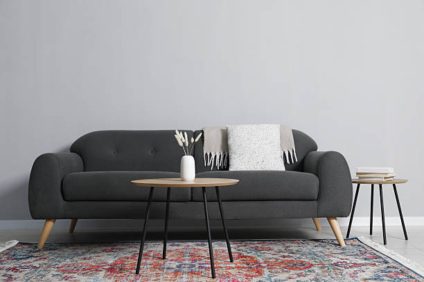istock Comfortable sofa and tables near grey wall in room 2214477161