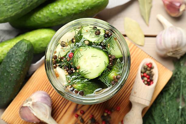 istock Making pickles. Fresh cucumbers and spices in jar on wooden table, top view 2214477610