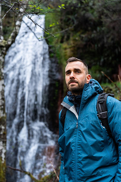 istock Hiker contemplating waterfall in lush forest 2214480636