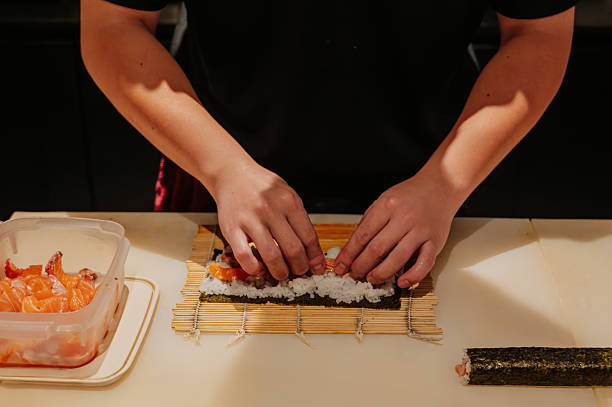 istock Chef's hand rolling up sushi on a bamboo mat. 2214481310