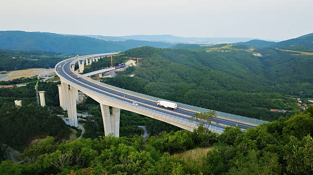 istock Highway bridge spans lush green hills, connecting cargo distribution routes. 2214484464
