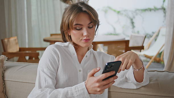 istock Relaxed brunette scrolling smartphone making online purchases at couch closeup. 2214485900