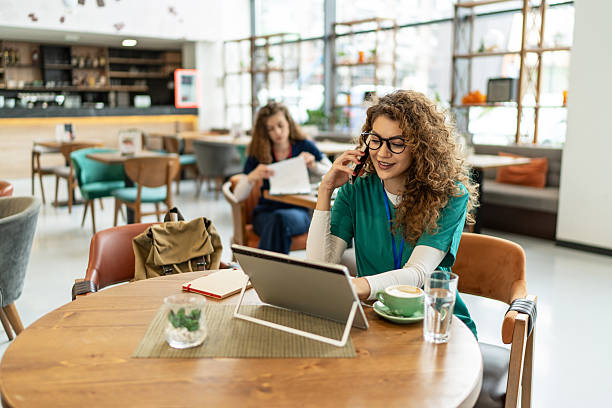 istock Young nurse working on tablet and talking on phone during coffee break 2214488372