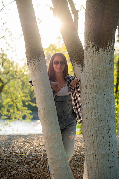 portrait of a beautiful woman leaning against a tree and looking at the camera