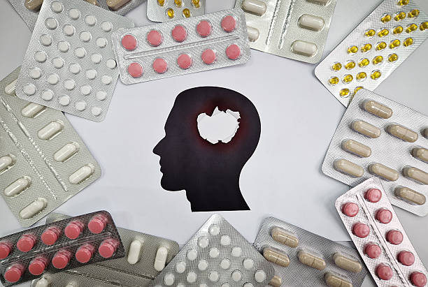 istock Various blister packs of pills arranged around a head silhouette with an explosion hole inside. Drugs of different shapes and colors for mental problems treatment. Pharmaceutical conceptual background 2214493473