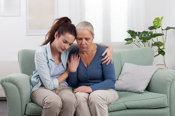 istock Granddaughter Hugs and Comforts Sad Grandmother at Home 2214497462