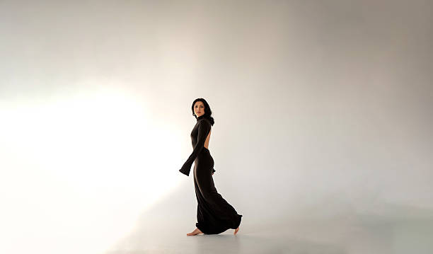 istock Brunette in a long black dress with an open back walks barefoot 2214498053