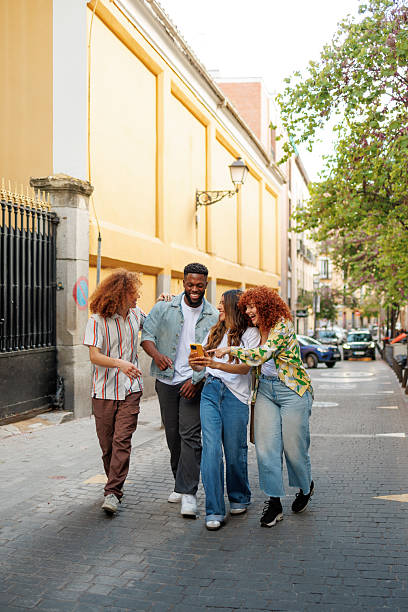 istock Multiethnic friends walking and using smartphone on city street 2214502189