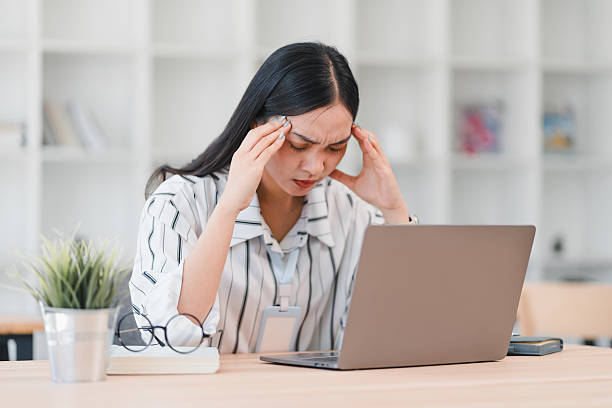 istock Asian woman experiencing stress while working on laptop in office setting. She appears frustrated and overwhelmed. 2214504349