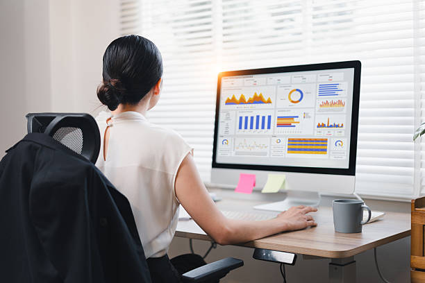 istock Asian businesswoman analyzing data on computer screen with charts and graphs in modern office. 2214506647