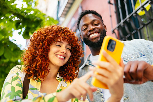 istock Two happy tourists are using a smartphone and smiling outdoors 2214506963