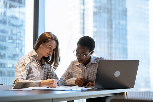istock Two Business Women Discussing Documents in a Modern Office Setting 2214514477