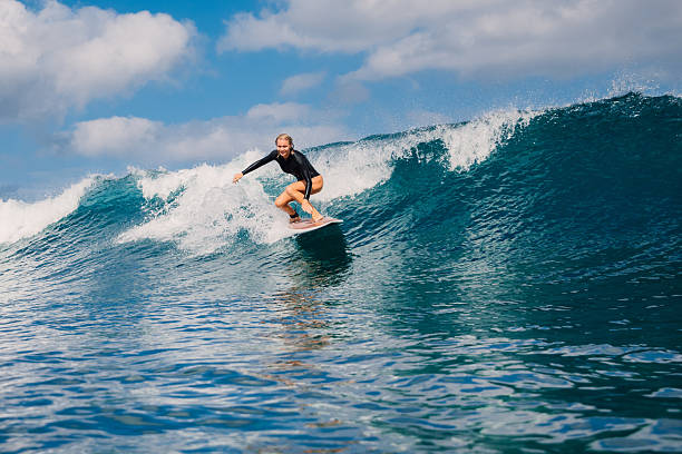 istock Smiling female surfer riding on ocean blue wave 2214516920