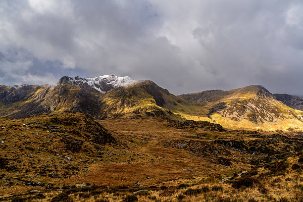 istock Snow-dusted Glyderau peaks rising above Cwm Idwal's glacial corrie basin under a brooding overcast sky 2214518993