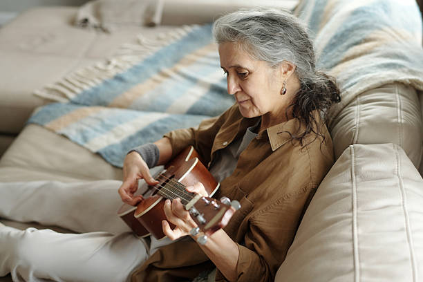 istock Playing Acoustic Guitar on Beige Couch with Striped Blanket 2214525898