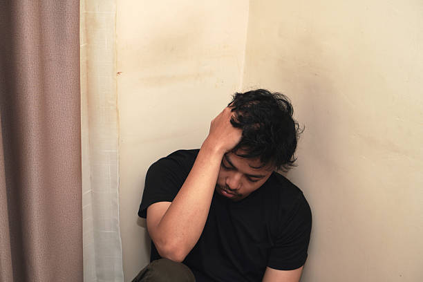 istock Depressed young asian man sitting on wall with hands holding head feeling miserable, lonely and sad. mental health depression concept 2214529865