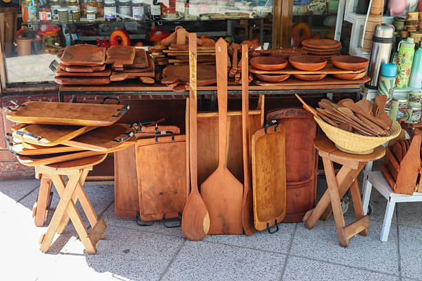 Handmade wooden utensils and boards, ready for sale next to rustic benches. Handcrafted spoons, plates, and bowls from Termas de Rio Hondo, Santiago del Estero