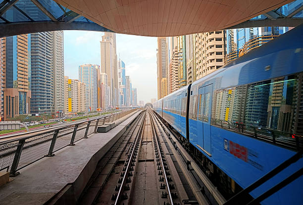 Dubai, UAE - March 4, 2025: Dubai metro train coursing between the two stations in the Trade Center district at sunset