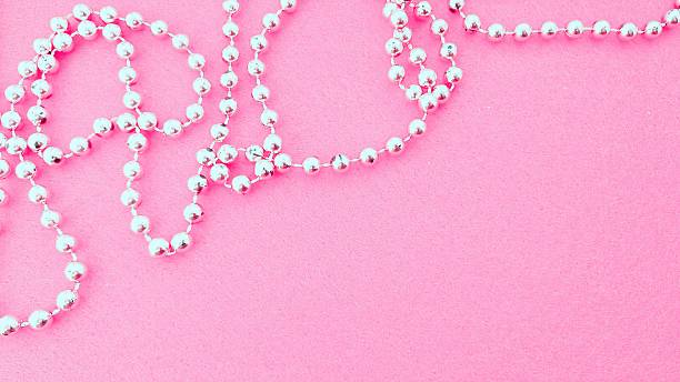 istock A silver beaded necklace on a pink background. 2214534287