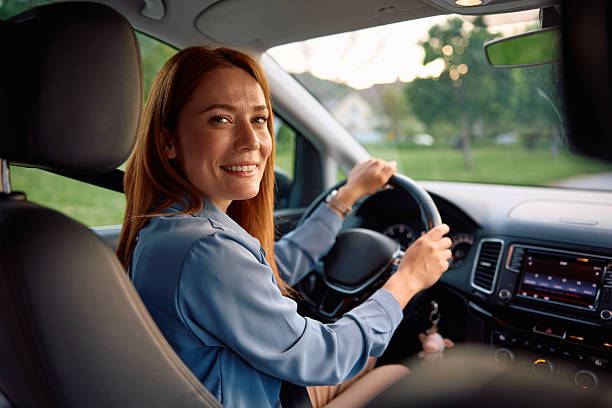 istock Happy woman parking in reverse and looking at camera. 2214535575