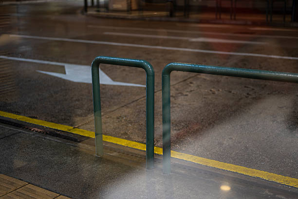 Urban street view through wet glass, capturing rain-soaked pavement and reflections. The scene conveys a moody atmosphere, ideal for atmospheric or urban photography projects.