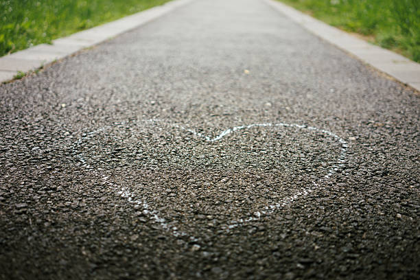 A heart drawn on the asphalt in a park during a spring day.