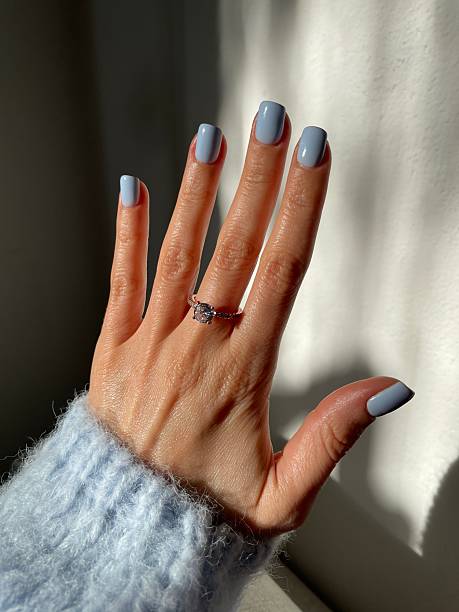 Woman's hand with light blue nail polish and a diamond ring