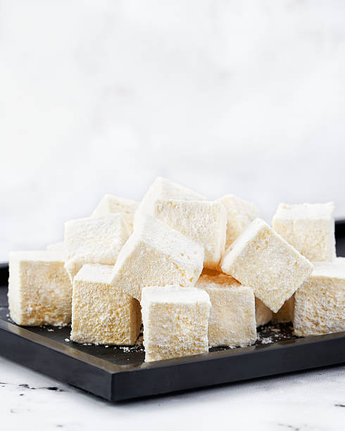 istock Pile of Vanilla Marshmallows Dusted with Icing Sugar on Black Plate over Marble Background, copy space for text. 2214544979