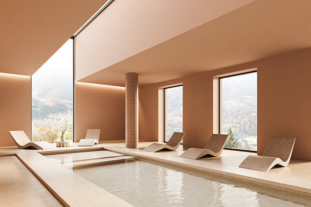 istock Modern indoor spa with minimalist lounge chairs and panoramic windows overlooking a serene mountain landscape in warm earthy tones. 3D Rendering 2214546610